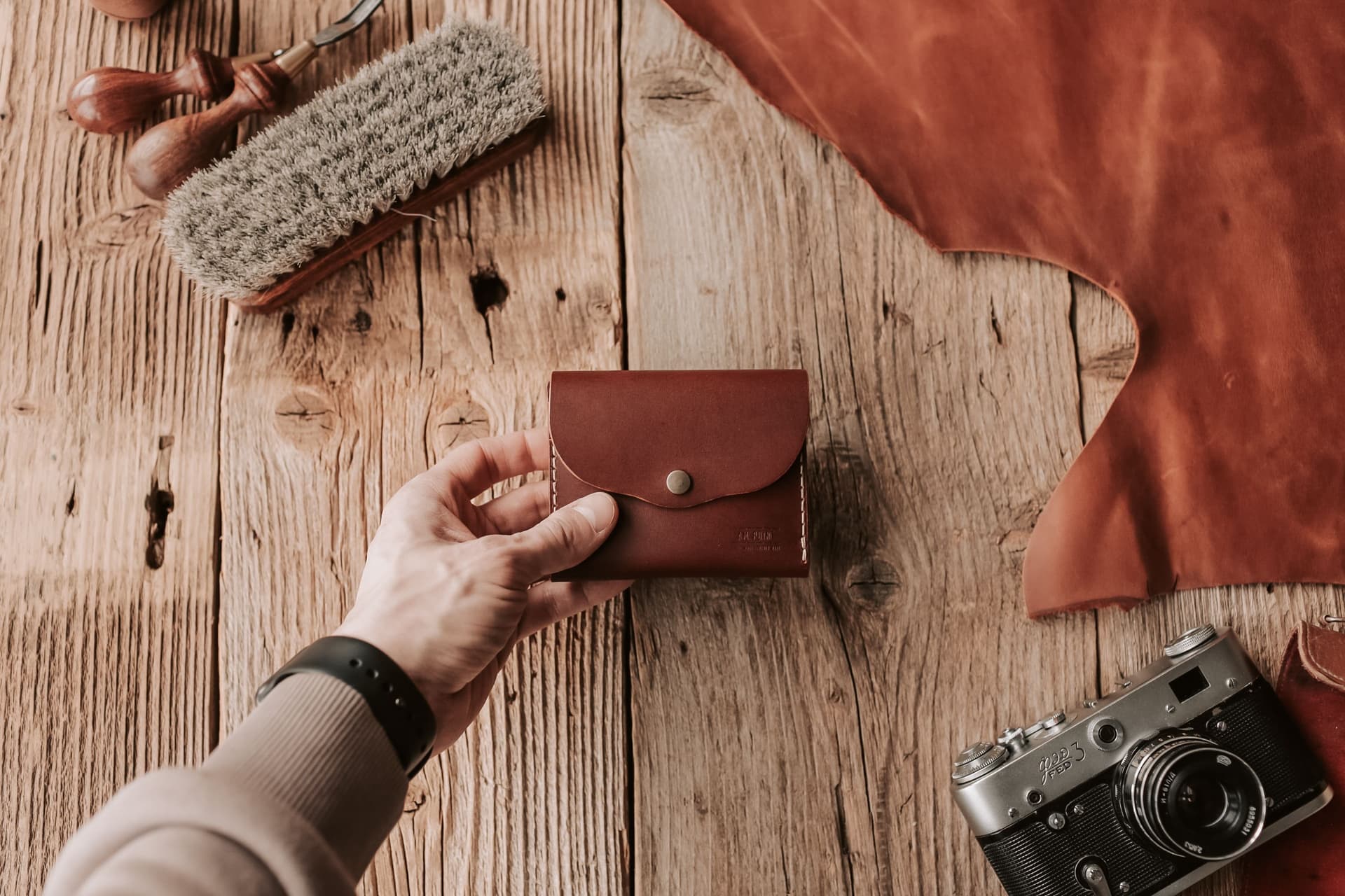 A slim brown leather wallet on a wooden surface, shot close up
